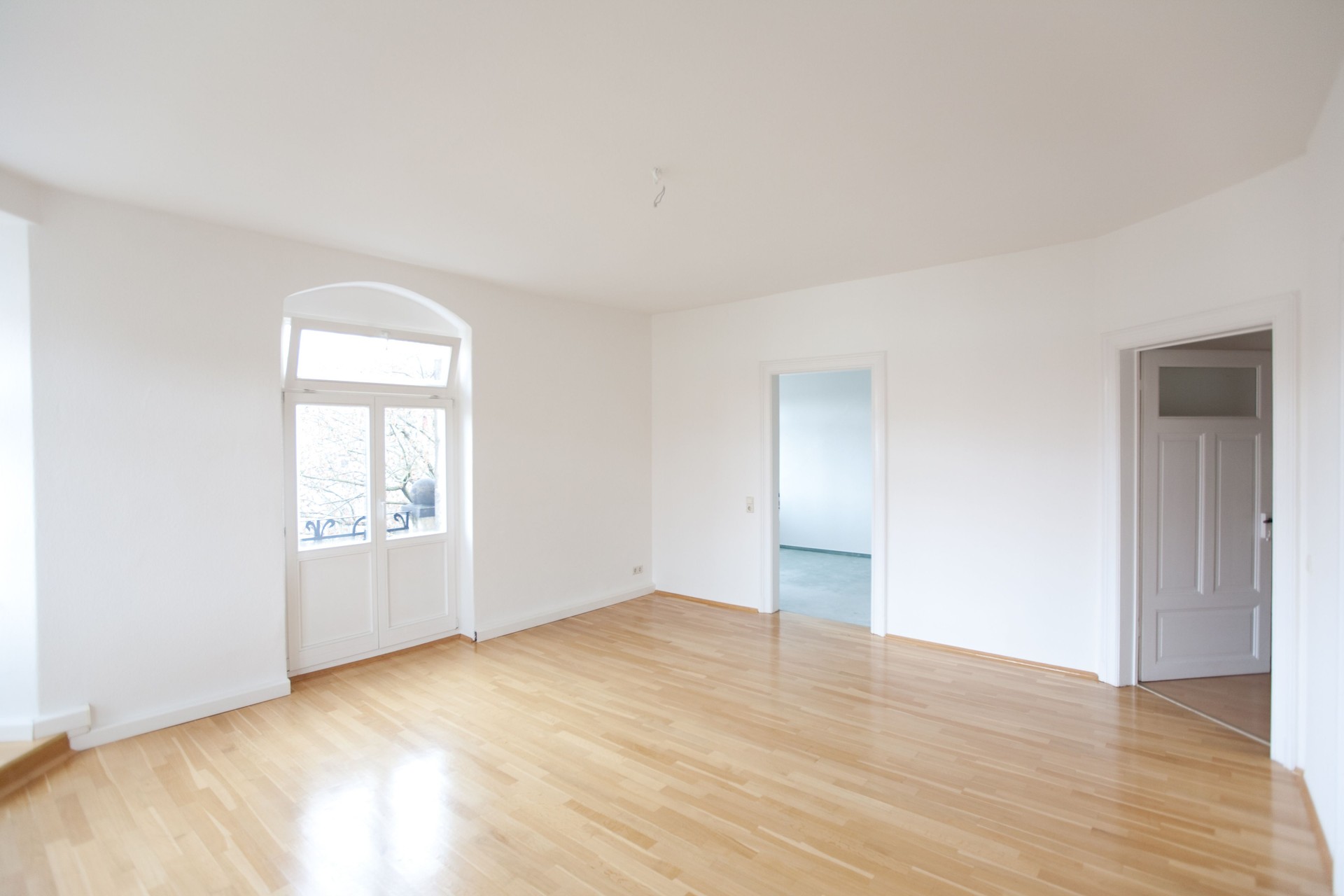 Empty all-white living room in a loft with tan wooden floors
